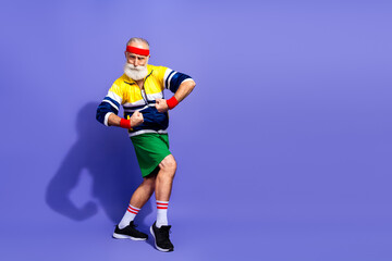 Elderly man in retro athletic wear posing for fitness and humor concept on vibrant colorful studio background © deagreez