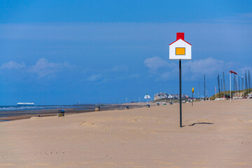 Wooden model of a house with a red roof on a pole on a sandy beach, coastal village De Haan, West Flanders, Belgium