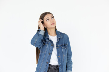 Young beautiful girl with long brown hair wearing jeans coat. freelancer looking away with confused disappointed expression, scratching head. student not remembers information for exam