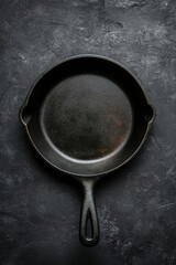 Empty cast iron frying pan on dark stone background