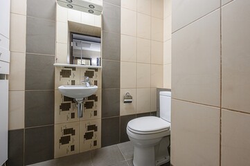 bathroom features a white toilet, sink with patterned backsplash, and neutral-toned tile