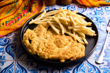 Chicken schnitzel or milanese with fried potatoes in a plate