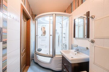 Cozy bathroom featuring a shower cabin, sink with vanity, and tiled walls