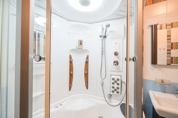 well-lit bathroom interior featuring a modern shower cabin and sink. The shower has various...