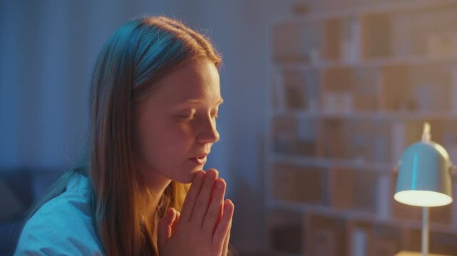 Young woman with Folded Hands Praying Quietly at Night, Peaceful Face in Soft Evening Light, Moment of Deep Faith, Hope, Spirituality and Mindfulness, Seeking Inner Peace and Personal Reflection.