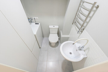 modern bathroom features a glass shower, toilet, towel warmer, and washing machine, all set against...