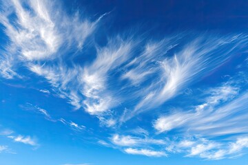 Whimsical, feathery clouds dance across a vibrant blue sky