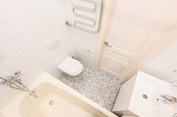 bright bathroom featuring white tiles, a cream-colored tub, a white sink, and a patterned floor
