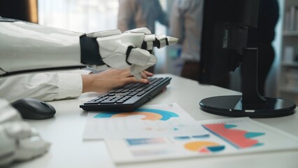 A robotic hand typing on a keyboard while surrounded by business reports and charts in a modern...
