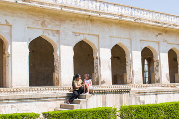 Indian mother and daughter sitting on the stairs of an ancient  Padmini Mahal of Chittorgarh Fort. capturing the essence of cultural heritage, family bonding, and candid joy during travel. 