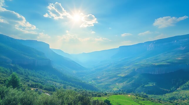 Landscape of green meadows and mountains under blue sky with clouds