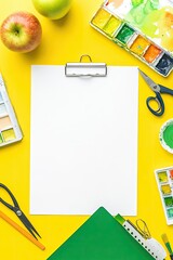 Blank paper centered on vibrant yellow surface, surrounded by art supplies and apples