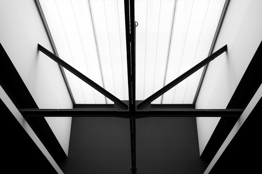 Black and white architectural photograph of steel ceiling beams with dramatic sunlight in museum interior
