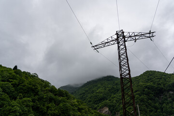 Support of power lines against the background of mountains and thick clouds
