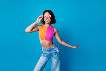 Young woman with stylish summer fashion posing confidently in vibrant pink sunglasses against a...