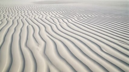 Abstract white sand dunes pattern created by wind, forming waves and ridges in a minimalist desert landscape. - Powered by Adobe