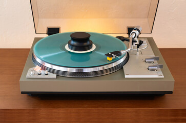Vintage Stereo Turntable Record Player With Turquoise Colored Disk and Weight Clamp Sitting on Wooden Console Cadenza Closeup