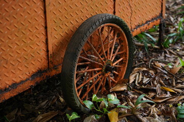 Rusty Orange Wheel on Old Cart Against Weathered Orange Metal