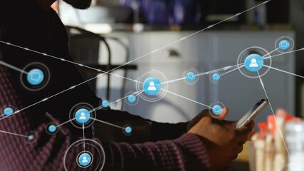 Man sitting at table holding smartphone and watching circular icon forming digital network - Powered by Adobe