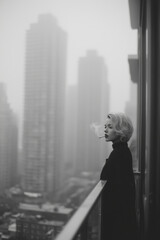 Woman enjoying a moment of reflection on a balcony overlooking the foggy city