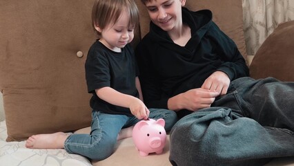 brothers put the coins in a piggy bank. Teaching financial literacy since childhood. older brother...