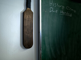 Vintage Wooden Paddle Hanging by Classroom Chalkboard with Heavy Vignette