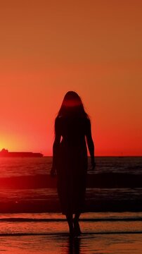Attractive Asian woman enjoys a walk on the beach at sunset in Southern California. Slow Motion. Vertical Video.