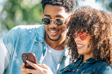 young latino couple looking at cell phone on the street