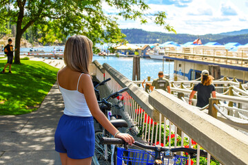 A young woman parks her bicycle at the lakefront marina in downtown Coeur d'Alene, Idaho at summer.