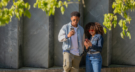 young latino couple looking at cell phone on the street
