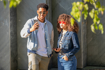 young latino couple looking at cell phone on the street