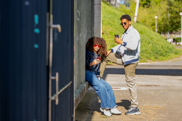 young latino couple looking at cell phone on the street