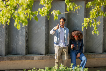 young latino couple looking at cell phone on the street