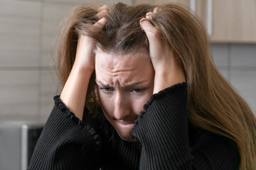 Portrait of a desperate young woman pulling her hair while experiencing a mental breakdown, highlighting the struggles of dealing with depression and anxiety