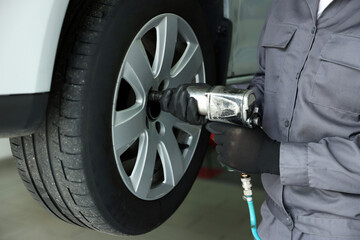 Mechanic changing tire at car service, closeup