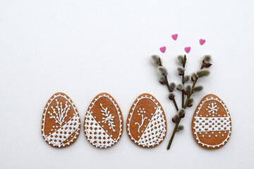 Romantic decorated Easter gingerbread cookies in a shape of egg, with willow twigs and small sugar hearts, copy space for text