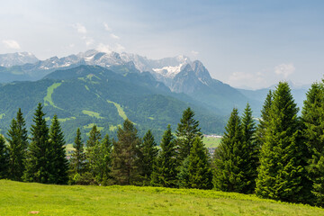 Hiking above the clouds on Wankberg, Germany—panoramic views of snow-capped Alps and lush valleys under a bright blue sky.