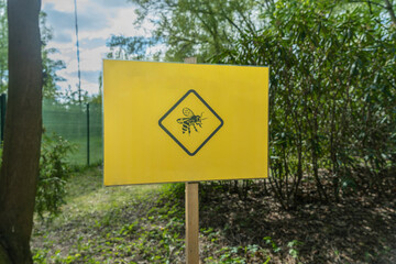 Warning bees - yellow sign featuring a bee in front of the beehive. Caution bees - homemade sign with a bee image in front of the apiary.