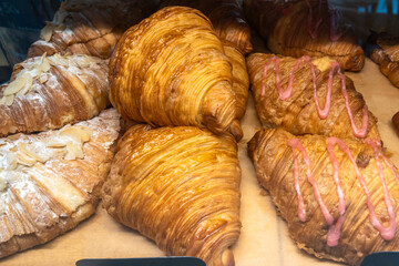 Freshly Baked Assortment Of Flaky Croissants With Almond Toppings And Sweet Icing In A Bakery Display.