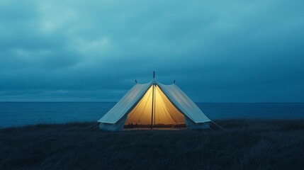 Illuminated Tent on Grassy Plain Under Overcast Sky at Night Near the Ocean