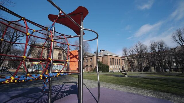 Playground with climbing structure surrounded by urban park on a sunny day with Academy of Dramatic Art building at background
