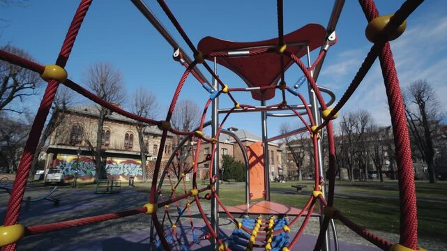 Vibrant urban park combines modern playground structures with classical architecture and street art on Academy of Dramatic Art building at background