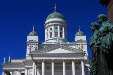 Finland Helsinki Lutheran cathedral and bronze figures from monument in foreground. Clear blue for sky copy space.