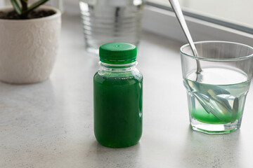 A bottle of aloe healing gel with a glass of gel diluted in water on the background of an aloe flower. The concept of using natural plants in the treatment of stomach diseases