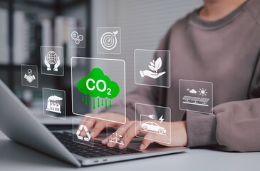 Carbon Emission Reduction and Sustainability Concept. Woman using laptop with icons environmental, CO2 reduction, renewable energy, and recycling, symbolizing sustainable and eco friendly practices.