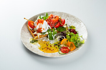 Potato waffle with trout and vegetables on a white table