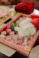 Floral Wedding Arrangement: A red tray filled with pink rose petals, white flowers, and a decorative jewel, creating a festive wedding decoration.