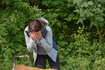 young athletic woman washing herself with water in the forest


