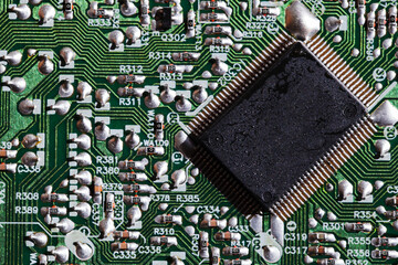 A  microchip soldered on an intricate green electronic circuit board