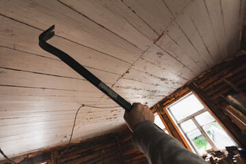 A hand gripping a crowbar in an indoor construction or renovation setting